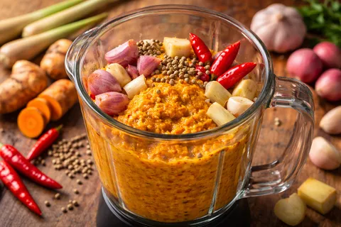 Bawang merah, bawang putih, halia, kunyit, serai dan biji ketumbar dikisarkan halus dalam blender menjadi paste perapan berwarna kuning-oren