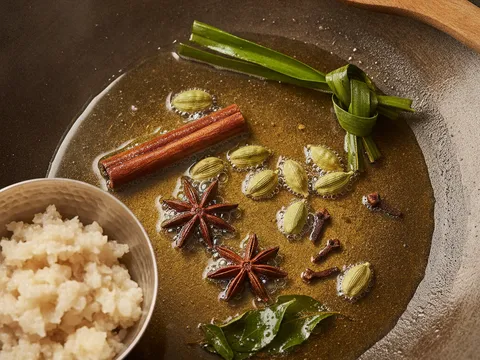 Kayu manis, bunga lawang, buah pelaga dan cengkih ditumis bersama daun pandan dan daun kari dalam kuali berminyak