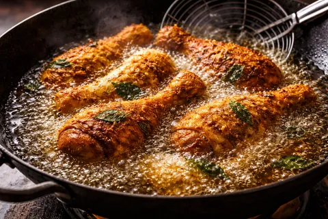 Ayam digoreng dalam minyak panas sehingga keemasan rangup