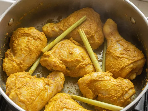 Ketul ayam bersalut pes cili kunyit kuning dimasak dalam periuk kering tanpa minyak
