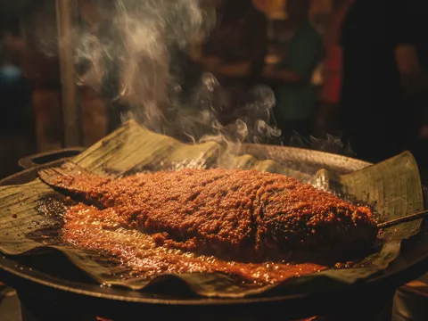 Ikan bersalut sambal merah dibakar atas daun pisang yang mula kehitaman di tepi dengan asap nipis naik