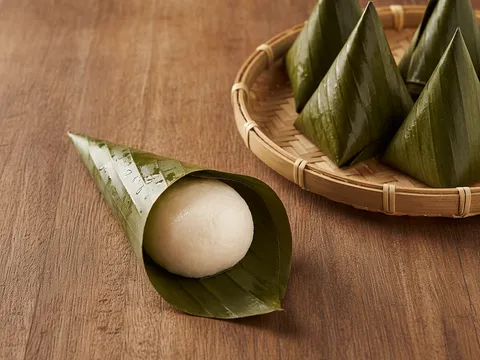 Doh kuih koci dimasukkan ke dalam kon daun pisang dan dilipat kemas berbentuk piramid
