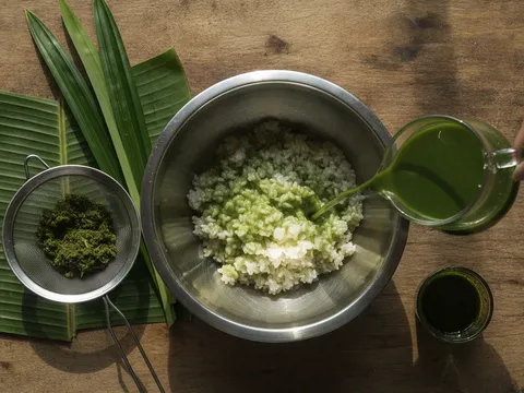 Beras pulut digaul dengan air pandan hijau dalam mangkuk, jag kecil air pandan di tepi