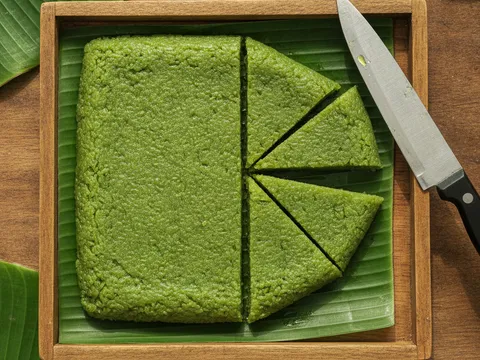 Pulut pandan padat dipotong bentuk segi tiga di atas daun pisang dengan pisau