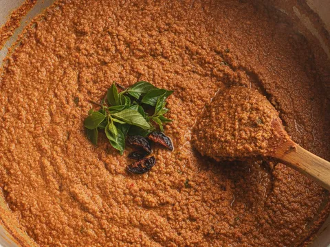 Kuah laksa Johor berwarna perang kemerahan direneh dalam periuk sehingga pekat bersama daun kesum