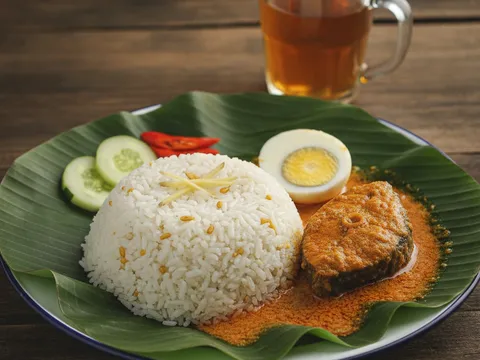 Hidangan lengkap nasi dagang Terengganu dengan gulai ikan tongkol, telur rebus dan acar timun di atas daun pisang