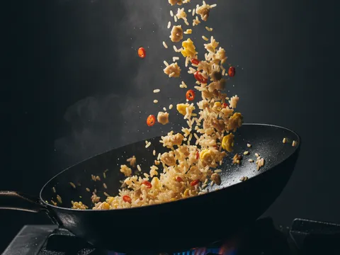 Nasi putih dimasukkan ke dalam wok atas api besar dan digaul dengan ayam, telur dan cili sehingga berderai