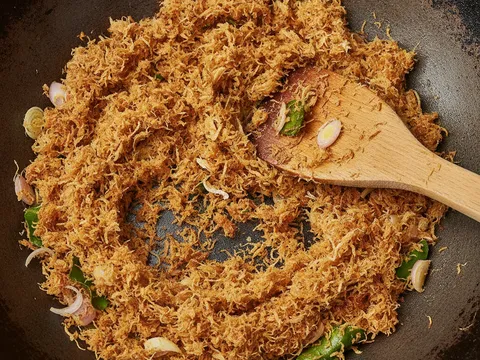 Sambal kelapa ikan disangai kering dalam kuali sehingga keemasan dan wangi