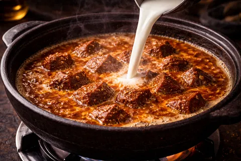Santan cair dan asam keping dimasukkan, daging direneh sehingga empuk