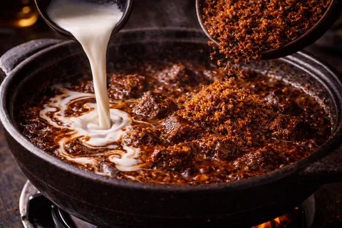 Santan pekat dan kerisik dimasukkan ke dalam rendang